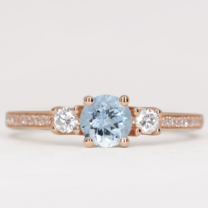 Round cut aquamarine and diamond trilogy engagement ring with white diamond pave band