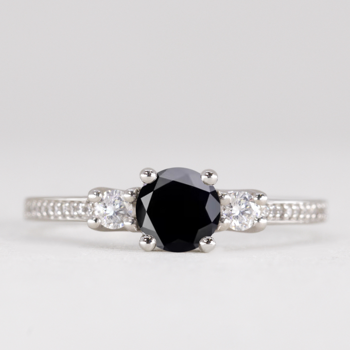 Round cut black diamond and white diamond trilogy engagement ring with white diamond pave band