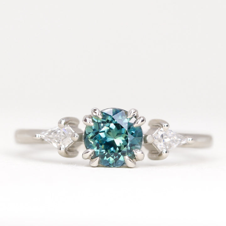 Round teal sapphire with white diamonds engagement ring in platinum