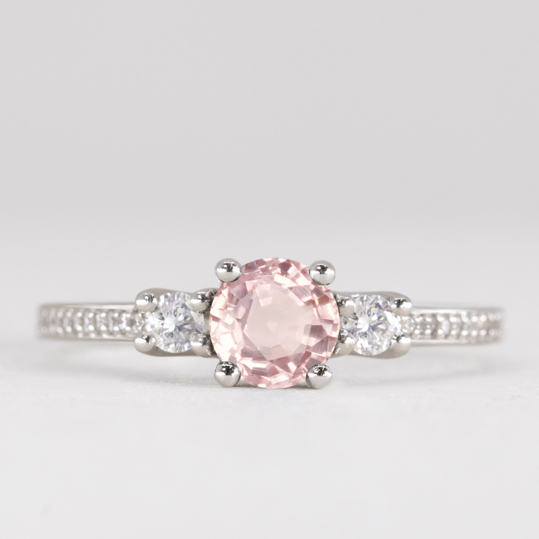 Round cut morganite and diamond trilogy engagement ring with white diamond pave band