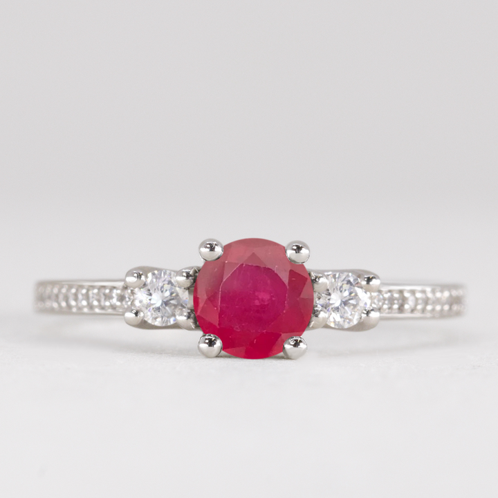 Round cut ruby and diamond trilogy engagement ring with white diamond pave band