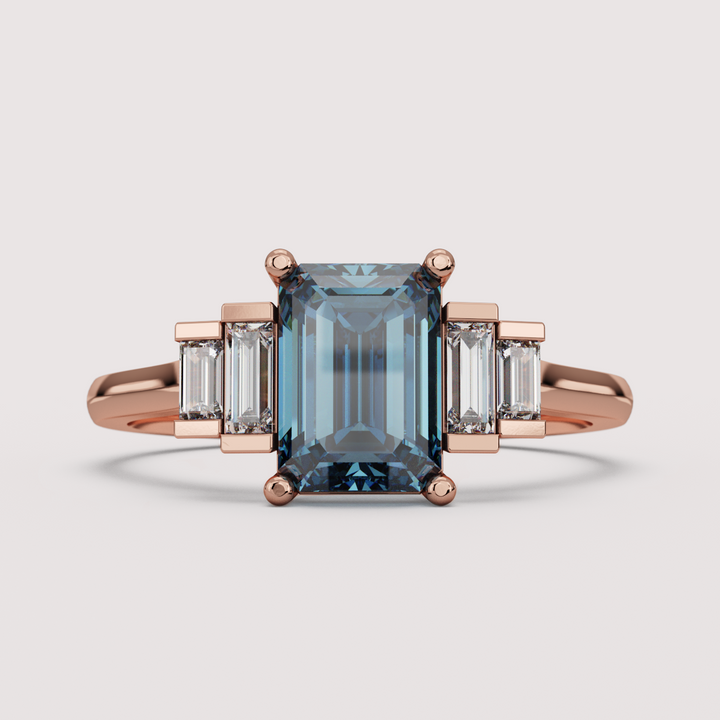 Rose gold ring with a blue gemstone and baguette diamonds on a light gray background